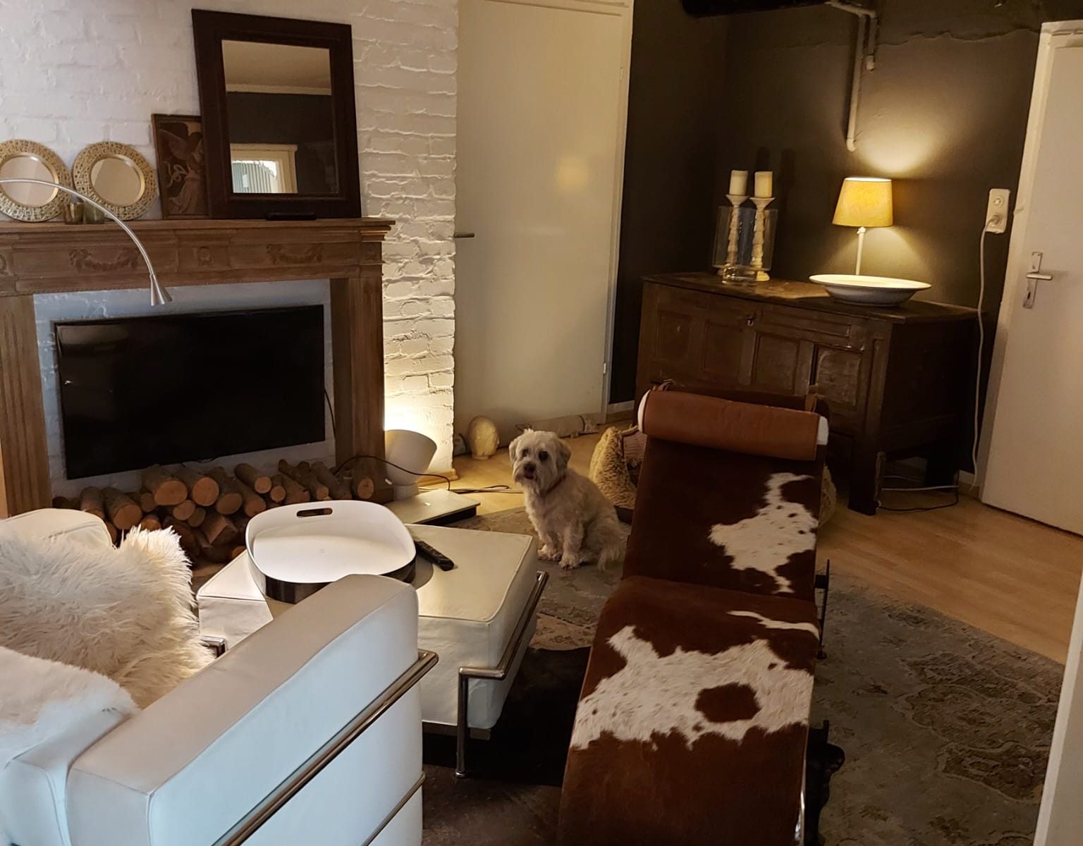 Entdecken Sie eine Wohlfühloase in unserem Behandlungszimmer, gekennzeichnet durch eine gemütliches Sofa und eine Kuhfellliege mit warmem Kerzenlicht. Tauchen Sie ein in die Geborgenheit und den Komfort dieser entspannenden Umgebung.